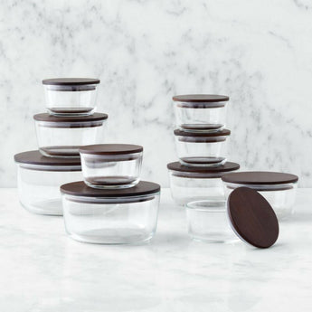 Crate & Barrel 8-Piece Round Glass Storage Containers with Dark Wood Lids.