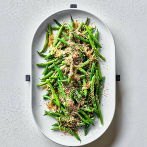 Bandeja ovalada para horno con salvamanteles de madera negra.