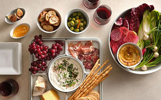 Super Bowl appetizer board with cheese, charcuterie, grapes, olives, hummus, crackers and wine for game day